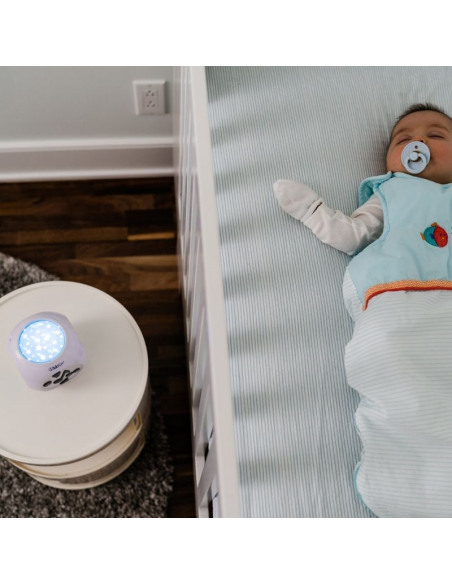 Kübe, proyector musical de noche para dormir al bebé encendido mientras un bebé duerme en una cuna